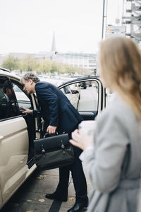 Side view of mature businessman by taxi in city