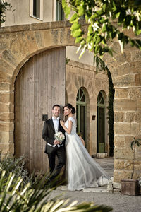 Portrait of wedding couple standing at arch gate