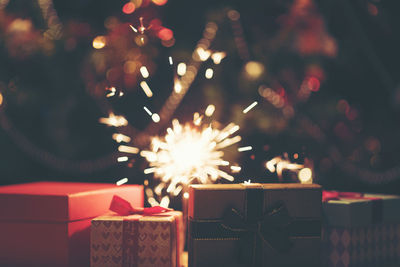 Close-up of sparklers and christmas gifts at night