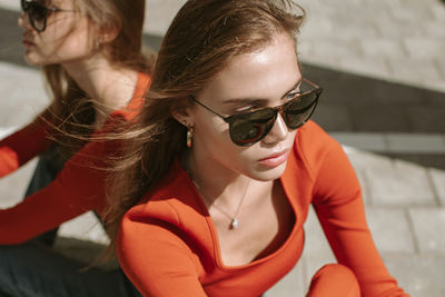 Portrait of twin sisters with hair fluttering in the wind in sunglasses with a confident look. 