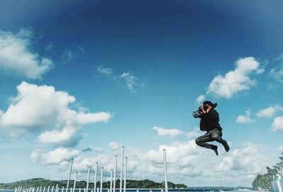 Low angle view of man jumping against sky