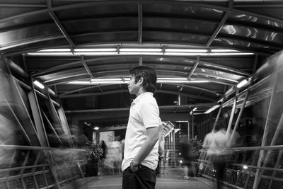 Profile view of man standing on illuminated covered footbridge at night