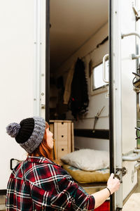 Side view of female hipster opening door of truck parked on beach near lake during summer trip