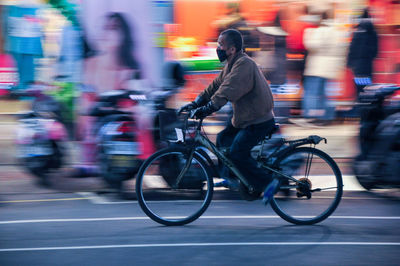 Blurred motion riding bicycle on road in city at night