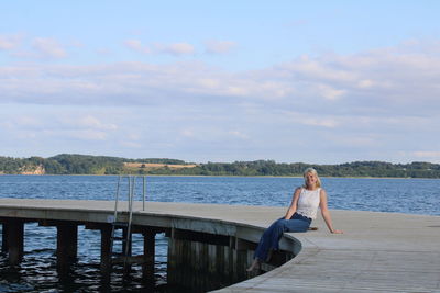 Rear view of woman standing at beach against sky