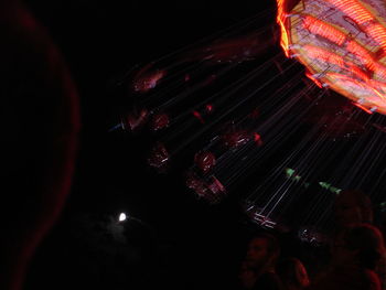 Low angle view of illuminated carousel against sky at night