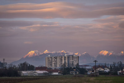 Houses and buildings against sky during sunset