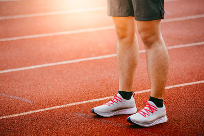 Low section of man standing on running track