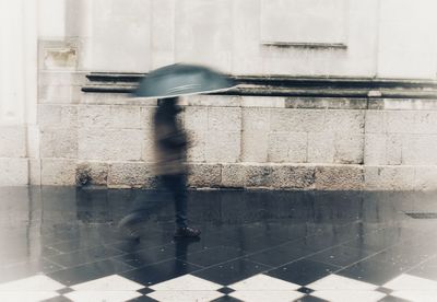 Blurred motion of man walking on footpath during rainy season