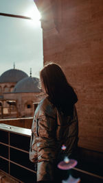 Rear view of woman in jacket looking at city buildings