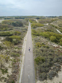 A man with long hair skating on a empty road in europe