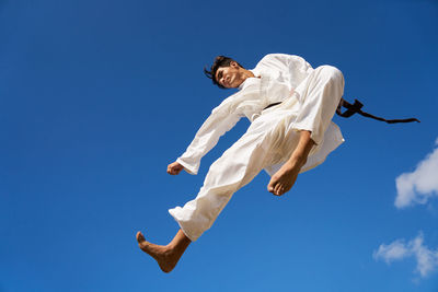 Low angle view of white jumping against blue sky