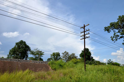 Low angle view of electricity pylon on field against sky