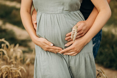 Pregnant woman standing with her husband holding big belly with baby 