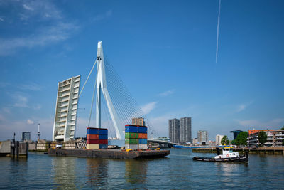 Tug boat towing barge with containers under open bascule part of erasmusbrug bridge