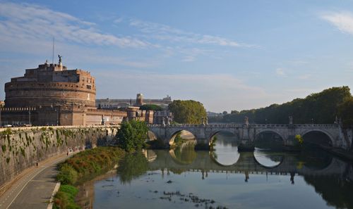 Arch bridge over river against cloudy sky