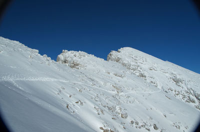 Scenic view of snowcapped mountains against clear blue sky