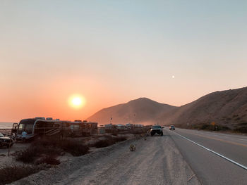 Cars on road against sky during sunset