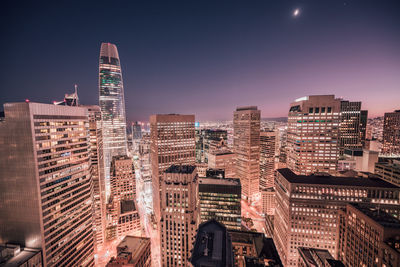 Illuminated buildings in city against sky at night