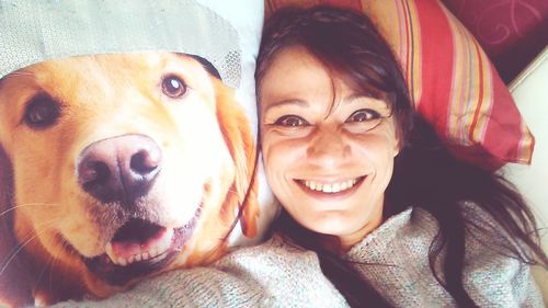 Portrait of young woman with dog on bed