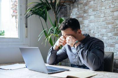 Young man using laptop while sitting on table