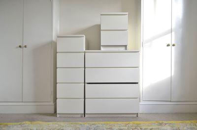 Stack of white boxes amidst closets against wall at home