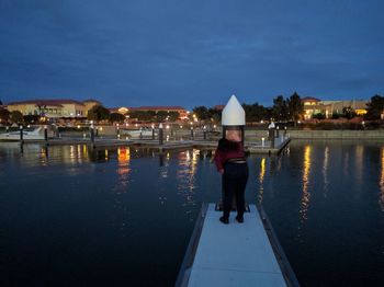 Rear view of man on harbor against clear sky at night