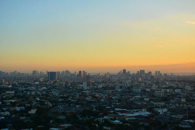 Aerial view of buildings in city against sky during sunset