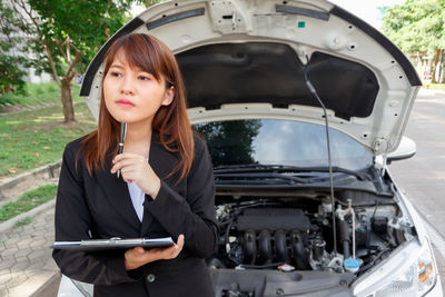 Portrait of young woman standing on a car