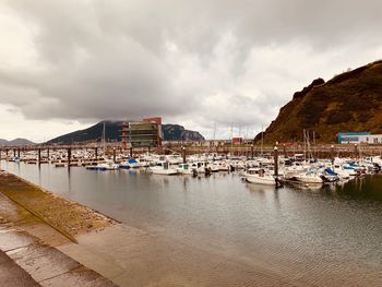 Boats moored at harbor against sky