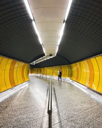 Rear view of man walking in illuminated tunnel