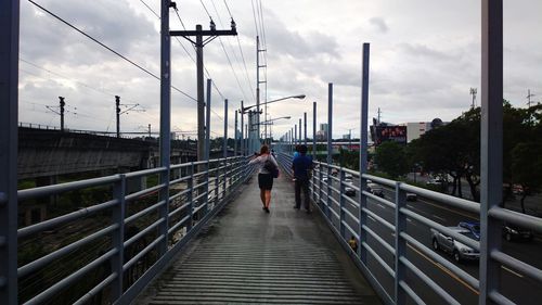 Man walking on bridge against sky