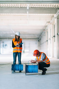 Architect with cables kneeling by coworker in parking lot