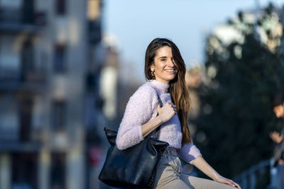 Portrait of smiling woman sitting in city