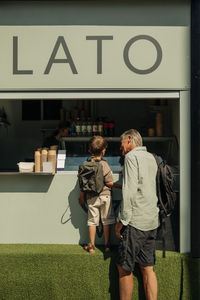 Grandson and grandfather buying ice cream while standing at concession stand