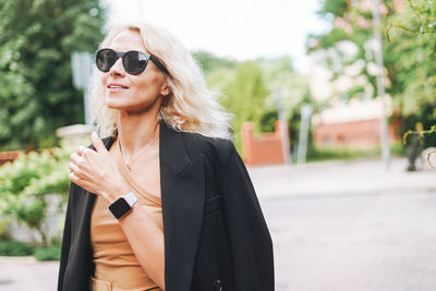 Young woman wearing sunglasses while standing in city