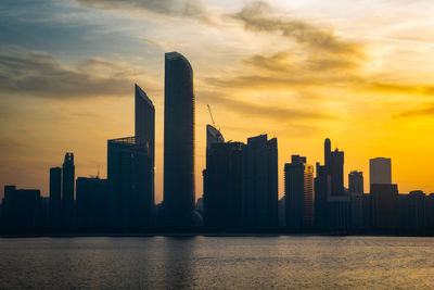 Modern buildings in city against sky during sunset