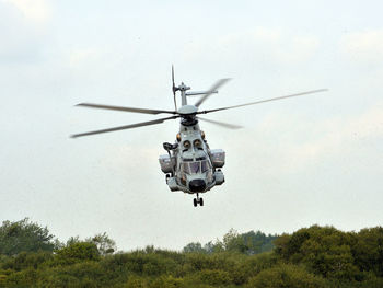 Helicopter flying over field against sky