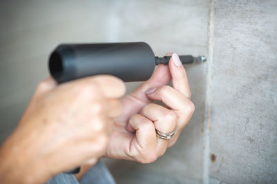 Close-up of hand holding eyeglasses against wall