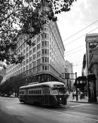 Cars on city street by buildings against sky