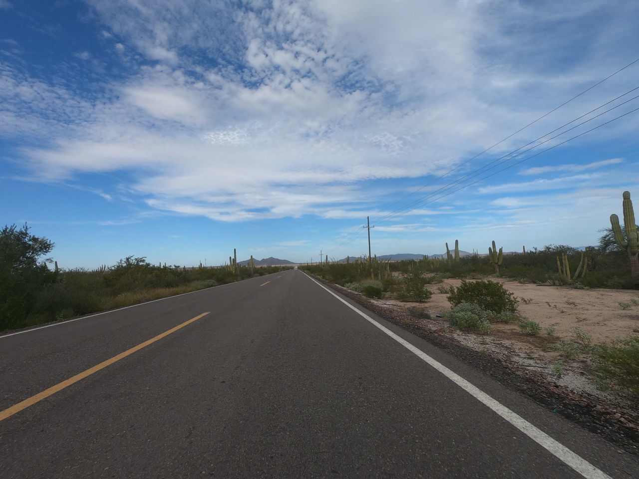 VIEW OF COUNTRY ROAD AGAINST CLOUDY SKY