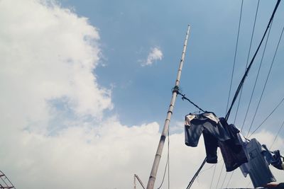 Low angle view of clothesline against cloudy sky during sunny day