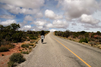 Rear view of person riding motorcycle on road against sky