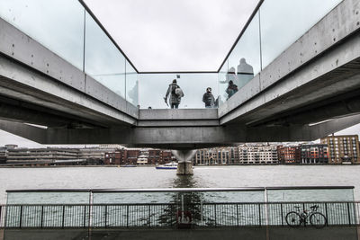 Low angle view of people at footbridge over thames river