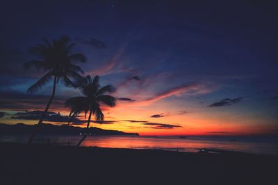 Silhouette palm trees on beach against romantic sky at sunset