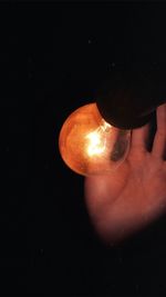 Close-up of illuminated light bulb against black background