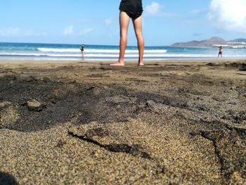 Low section of woman standing at beach against sky