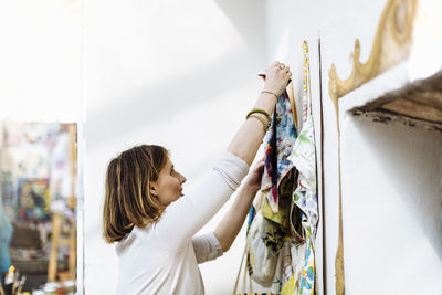 Female artisan hanging textile samples on wall in studio