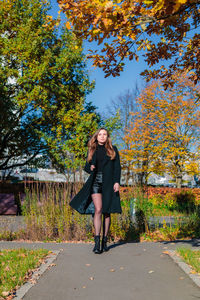 A woman with long hair walks alone along a path in an autumn park. autumn season concept. person