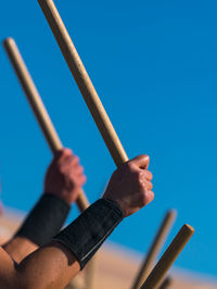 Close-up of hands against clear blue sky